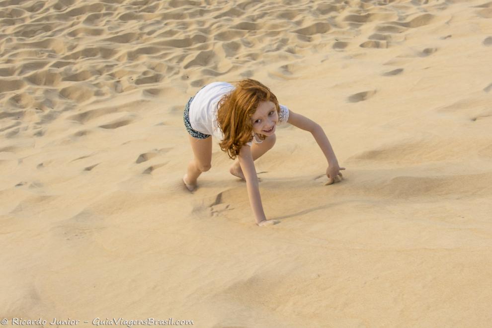 Imagem de criança brincando nas dunas da praia de Itaúnas
